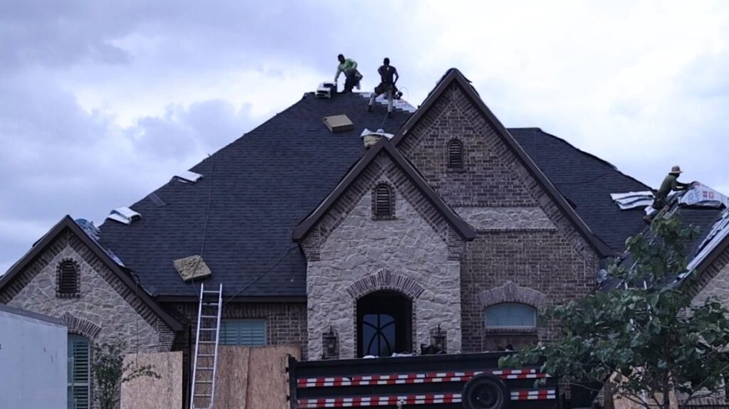 Roofers installing new shingles on a steep brick home in the Fort Worth area